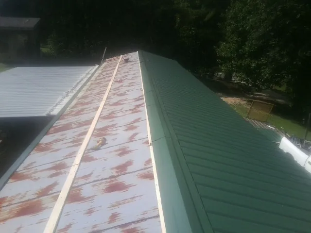Old rusted panels beside newly installed green metal roofing — Wind Damage Roof Repair by Roofing Brothers in Carlisle