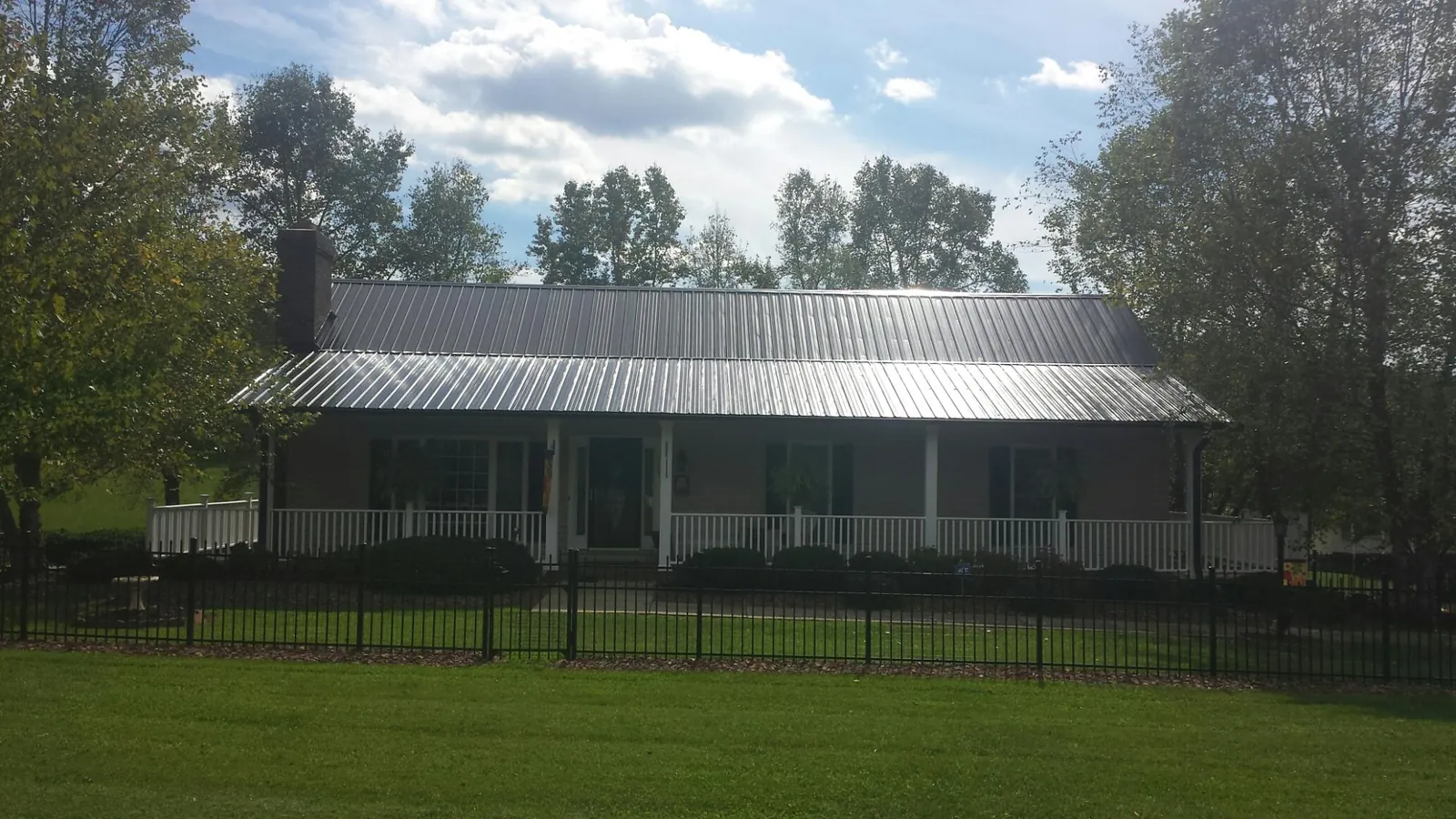 Gray metal roof on a brick ranch with a full width front porch — Gutter Guard Installation work by our crew in Carlisle